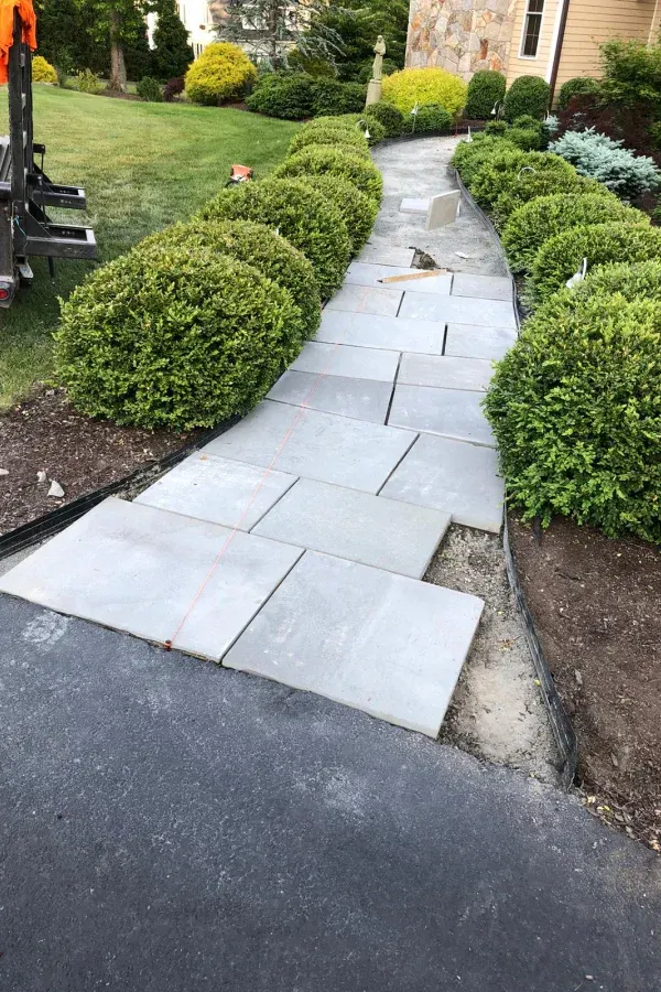 A walkway is being built in the backyard of a house.