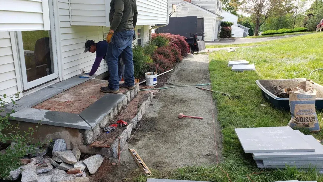 Two men are working on a porch of a house.