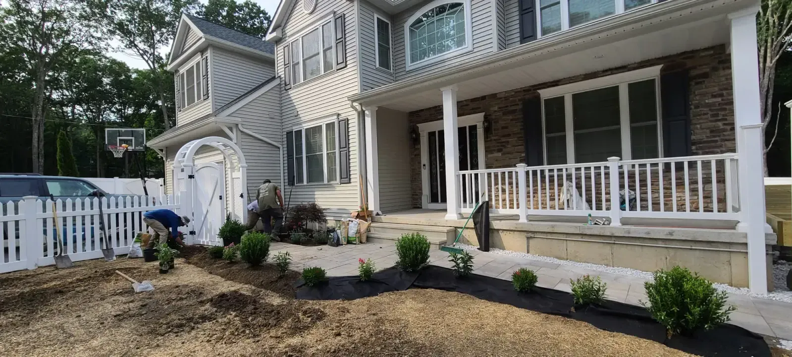 A large house with a white picket fence and a basketball hoop in the backyard.
