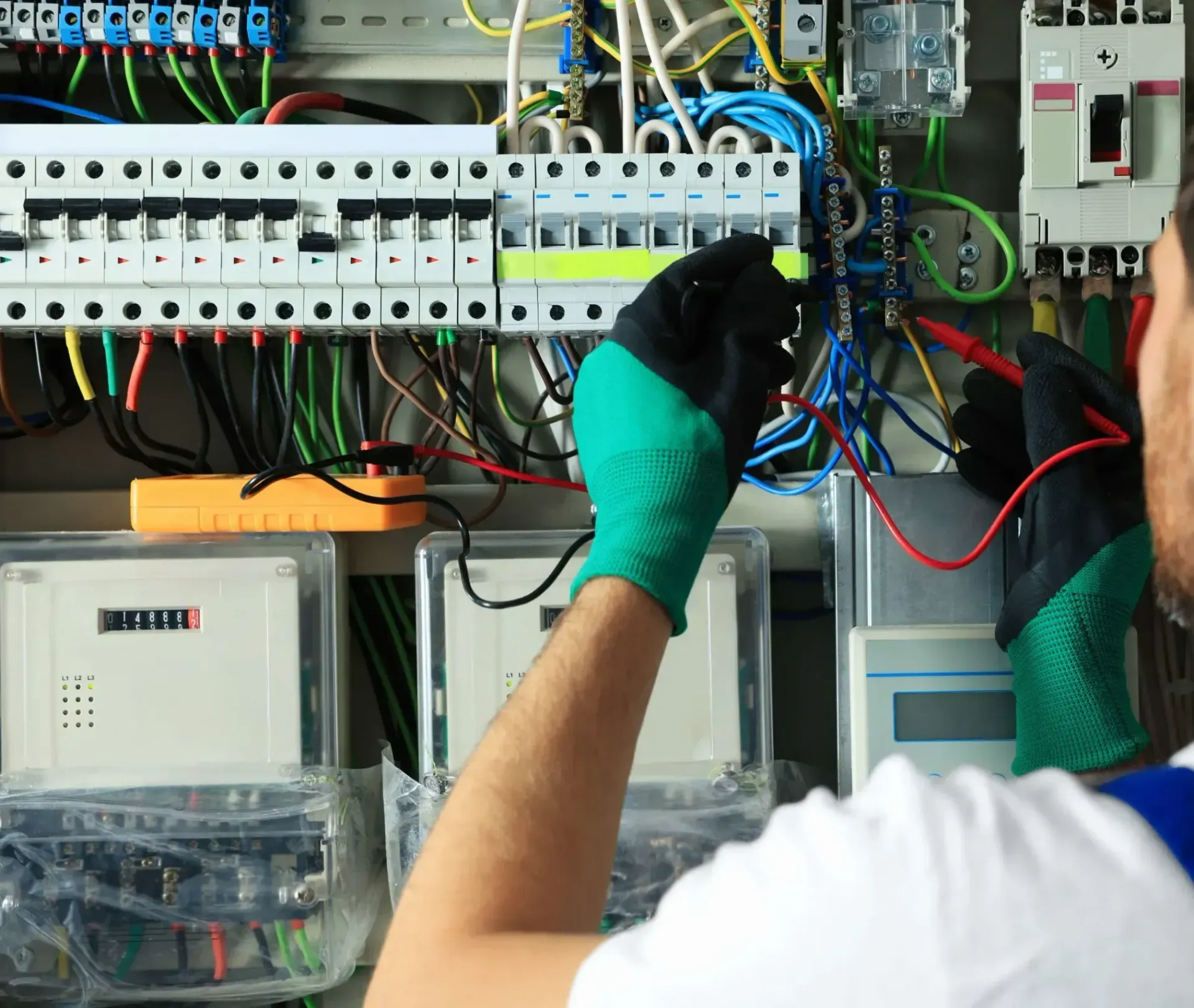 An electrician is working on a circuit board with a multimeter.