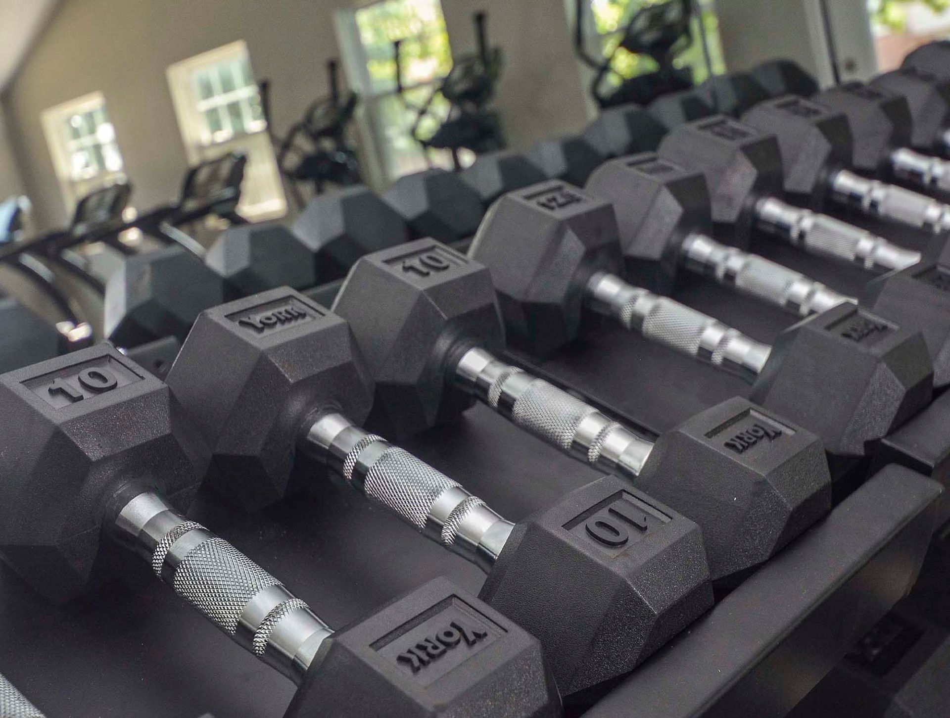 Rows of dumbbells with textured handles on a rack in a gym. Contact us today to learn more about our pet-friendly 1, 2, 3, and 4-bedroom apartments for rent in Bethlehem, PA. At River Pointe Townhomes, you’ll enjoy a prime location near Lehigh River and all the amenities and extras that make your life comfortable. We can’t wait to welcome you home!