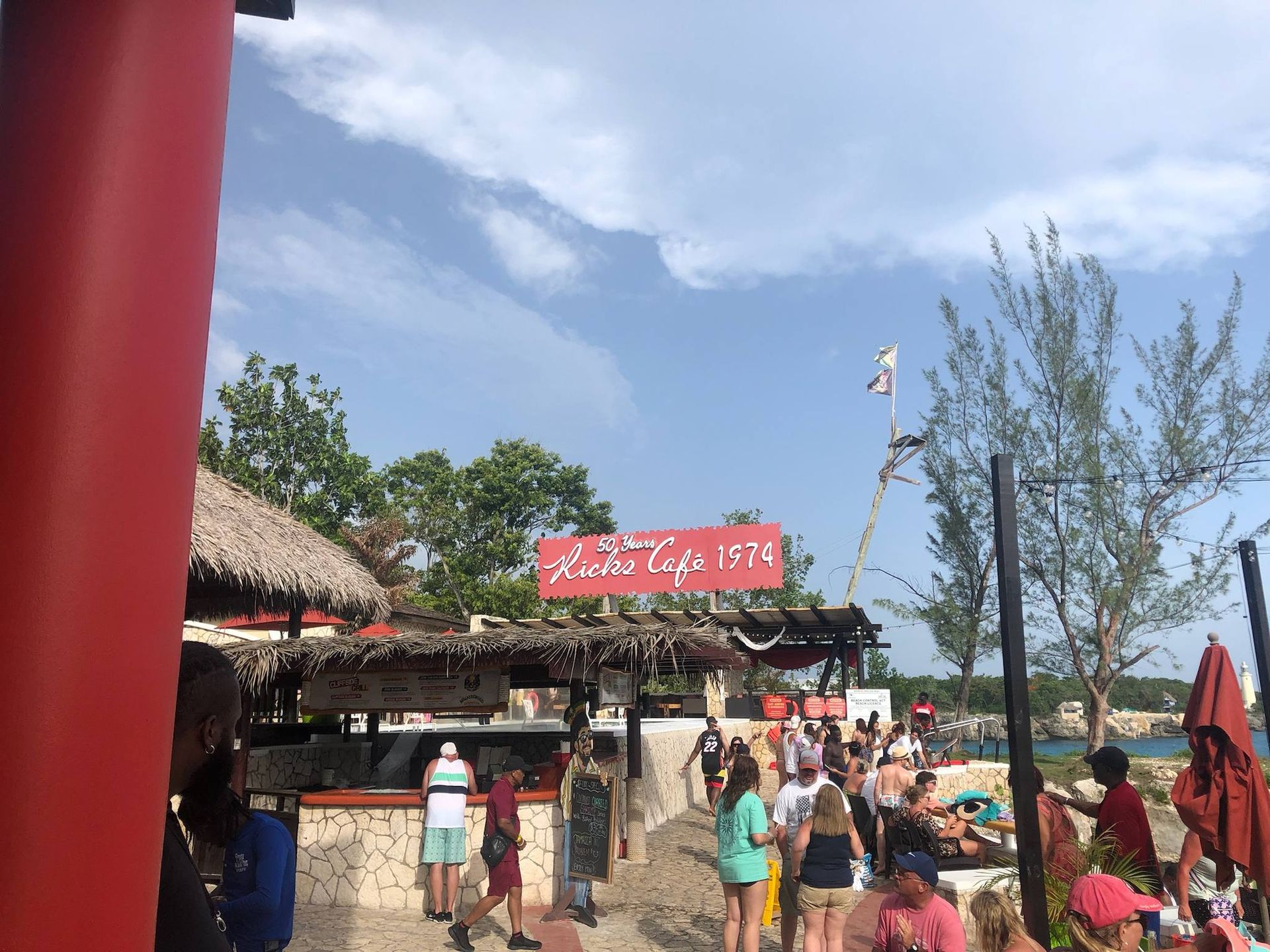 A group of people are standing in front of a restaurant on a beach.
