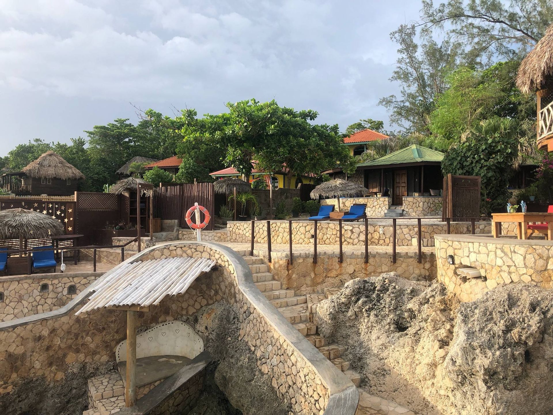 A staircase leading to a beach with a life preserver in the water.