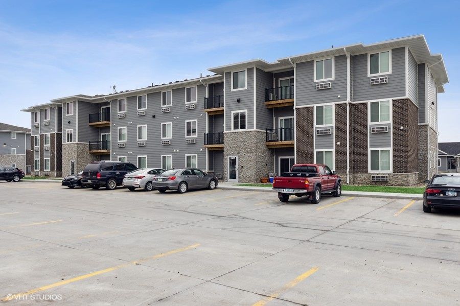 A large apartment building with cars parked in front of it.