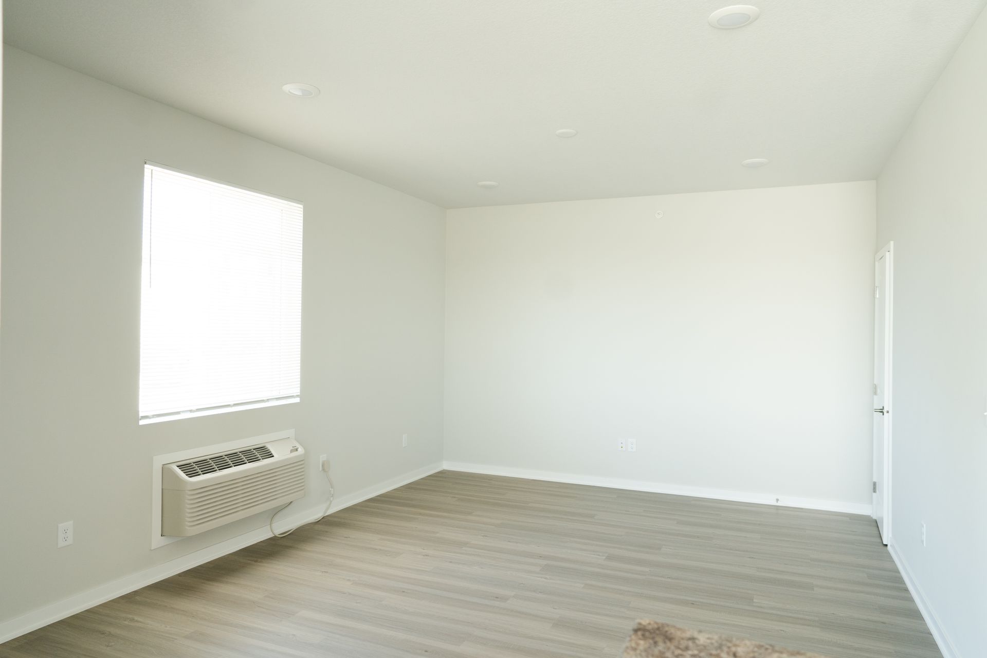 An empty room with a window and a heater.