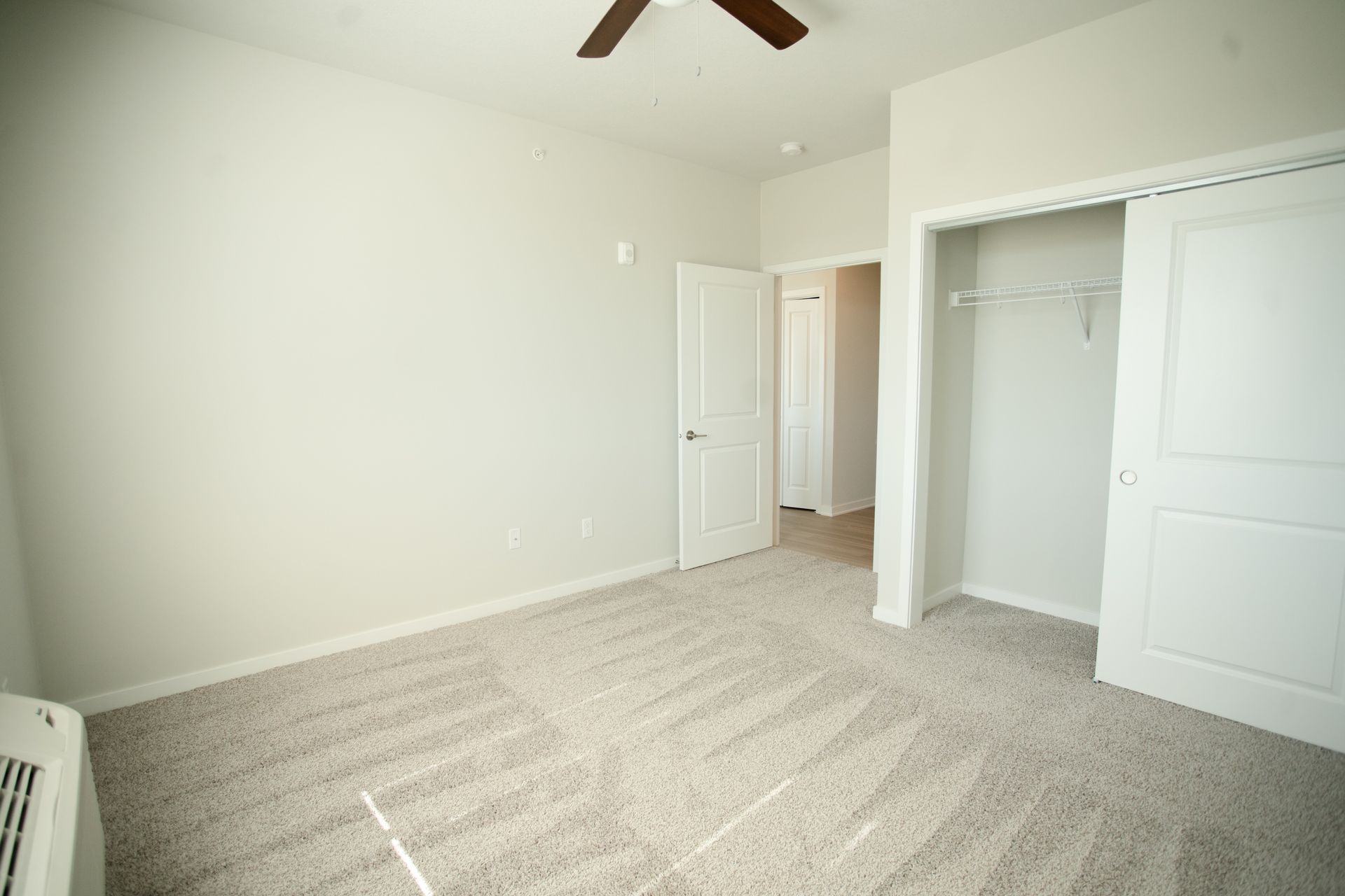 An empty bedroom with a ceiling fan and a closet.