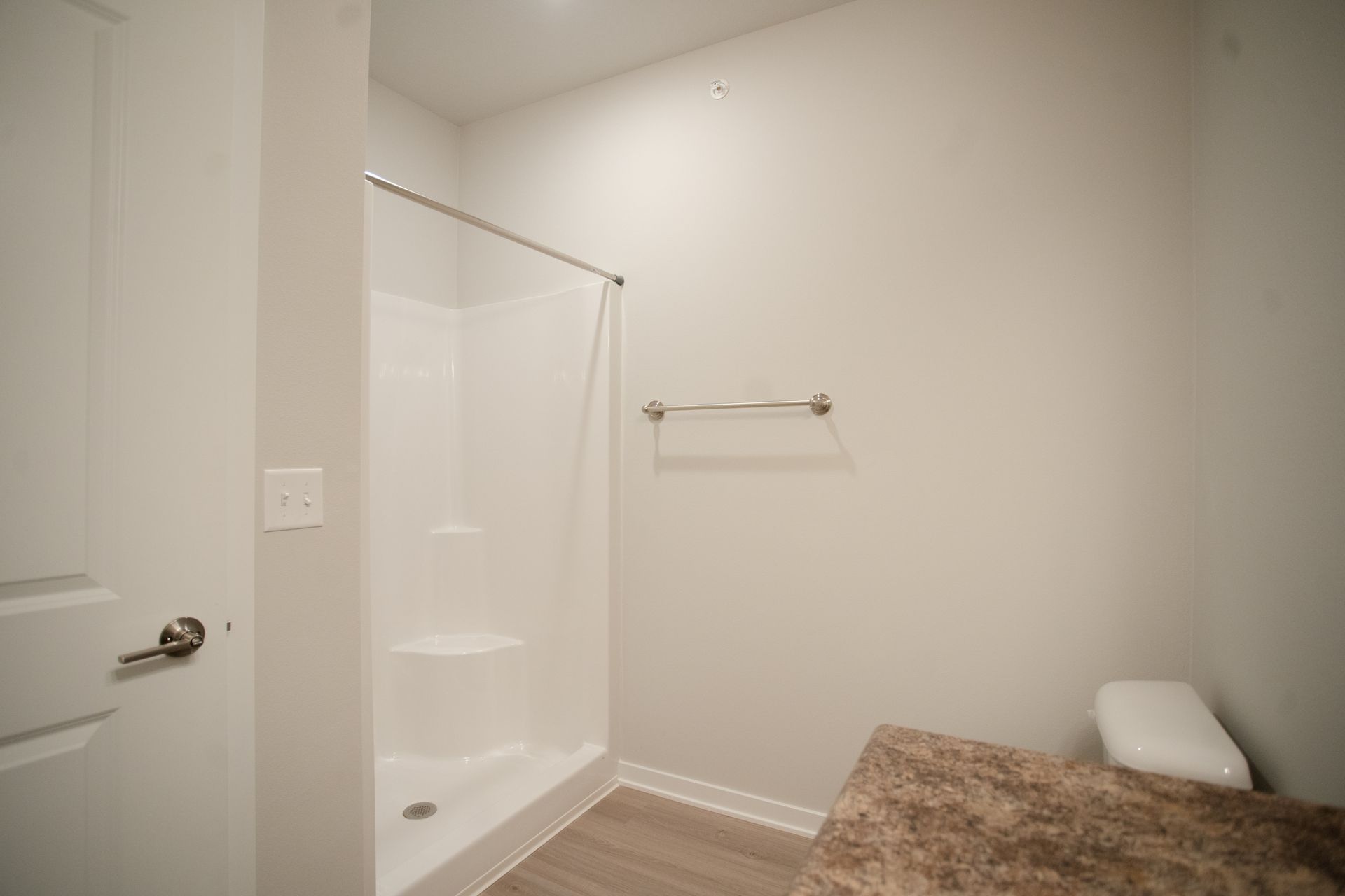 A bathroom with a toilet , shower , and towel rack.