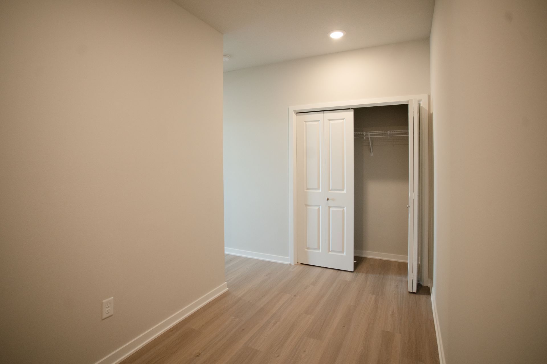 An empty bedroom with hardwood floors and a closet.
