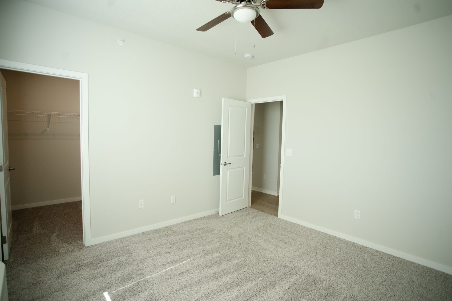 An empty bedroom with a ceiling fan and a walk in closet.