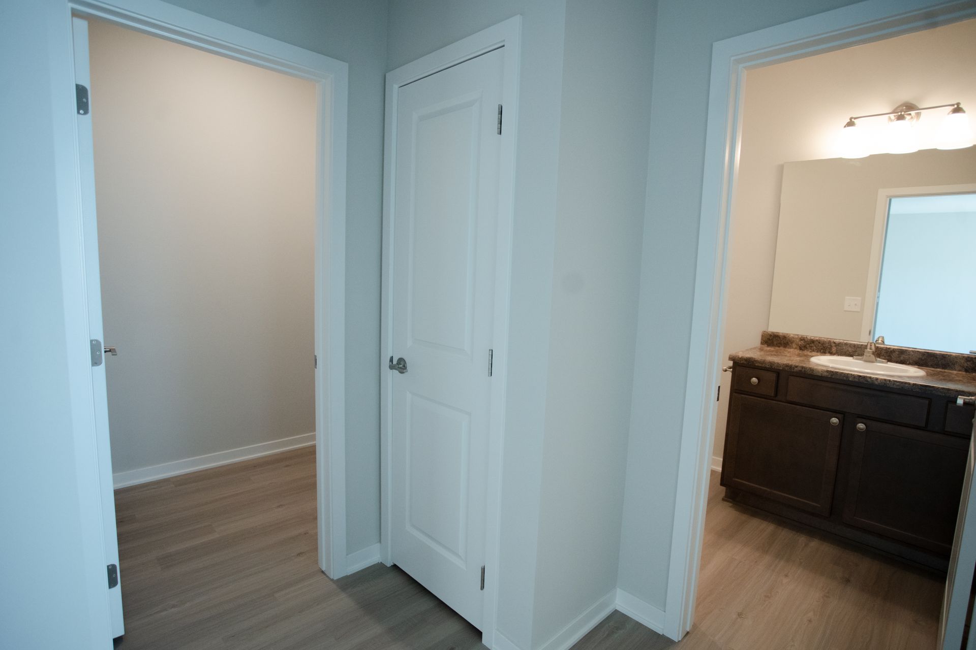 A hallway leading to a bathroom and a closet in a house.