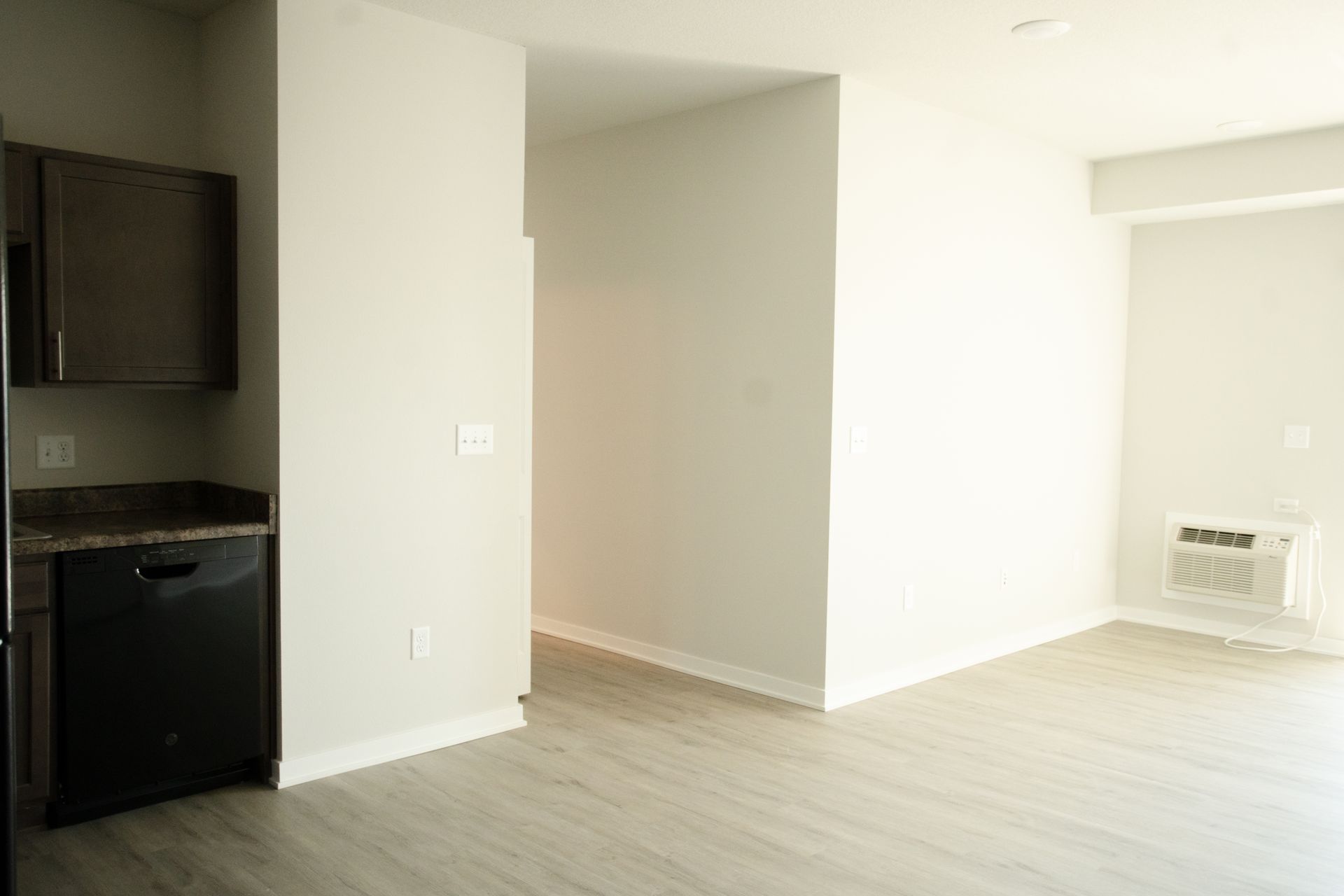 An empty apartment with a kitchen , dining room , and living room.