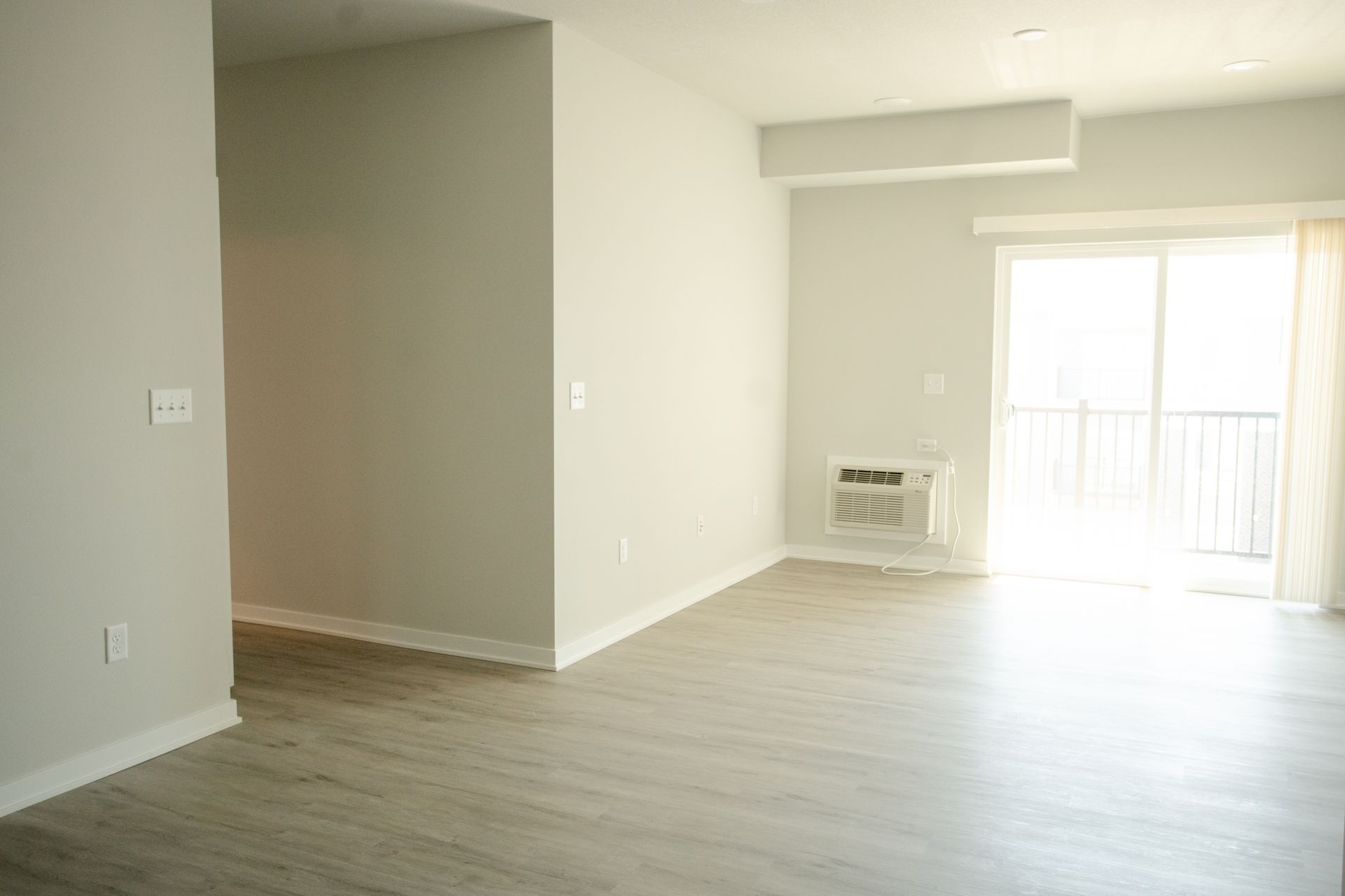 An empty living room with a sliding glass door and a window.