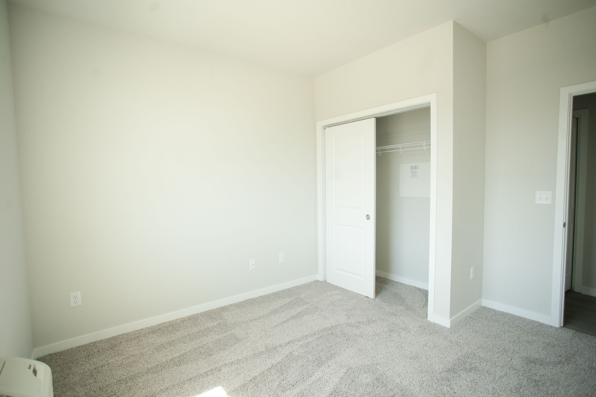 An empty bedroom with a closet and a carpeted floor.