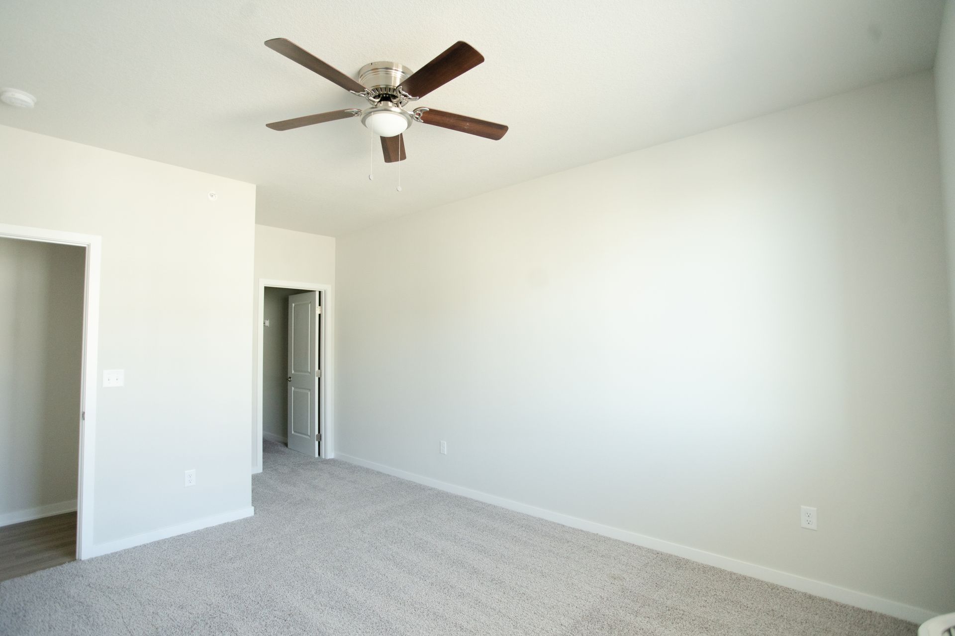 An empty bedroom with a ceiling fan on the ceiling