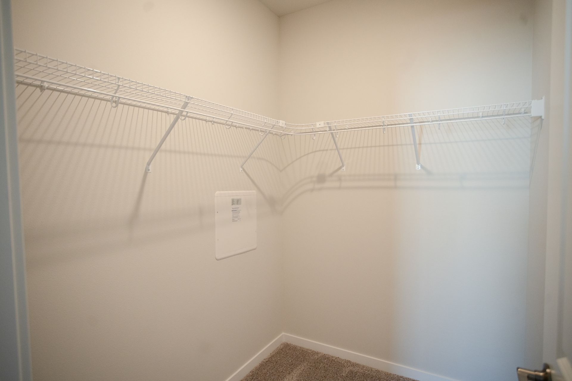 A walk in closet with a wire rack and a door.