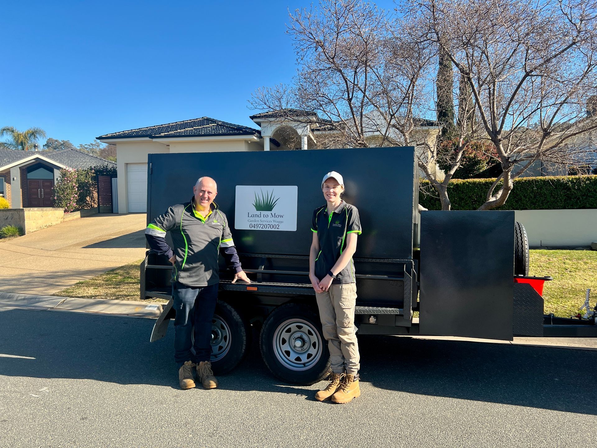 A Man and Woman Stand Next To Ute With Logo — Land to Mow Garden Services Wagga In Wagga Wagga, NSW
