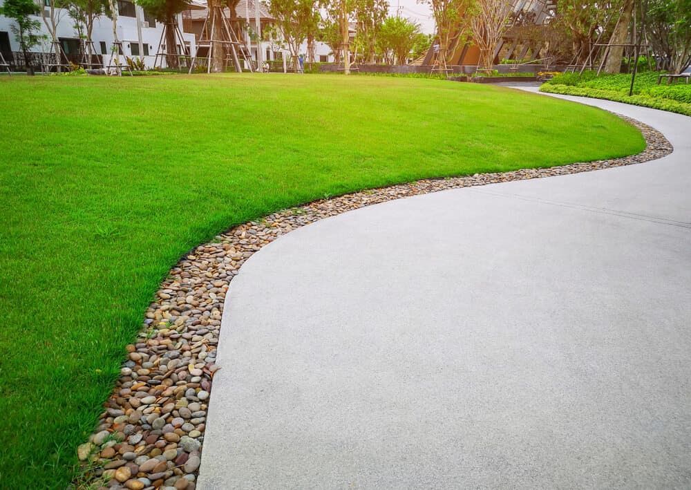 A Concrete Walkway Leading to a Lush Green Field in a Park — Land to Mow Garden Services Wagga In Wagga Wagga, NSW
