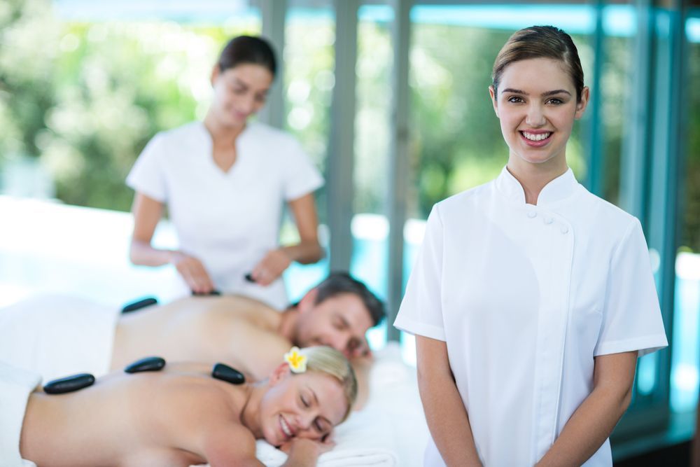 Spa Employee Smiles, Others Receive Hot Stone Massage — A1 Coffs Harbour in Coffs Harbour, NSW