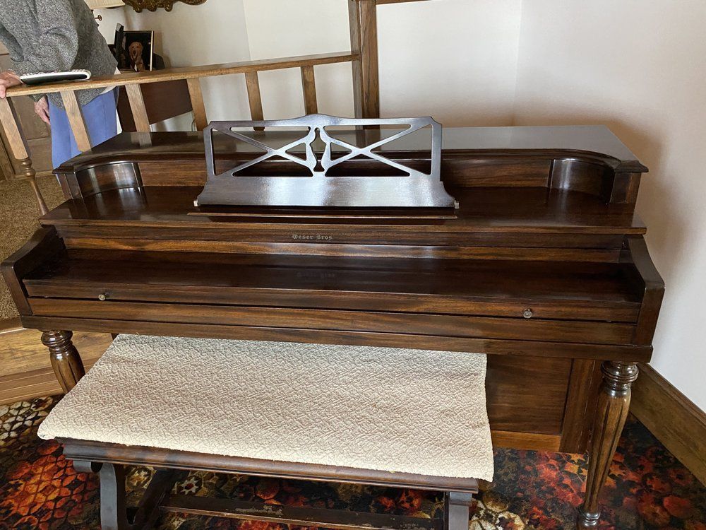 Dark wood piano with music stand and bench in a room with a patterned rug.