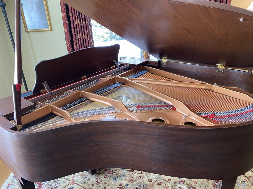 A grand piano with its lid open, revealing strings and internal mechanics.