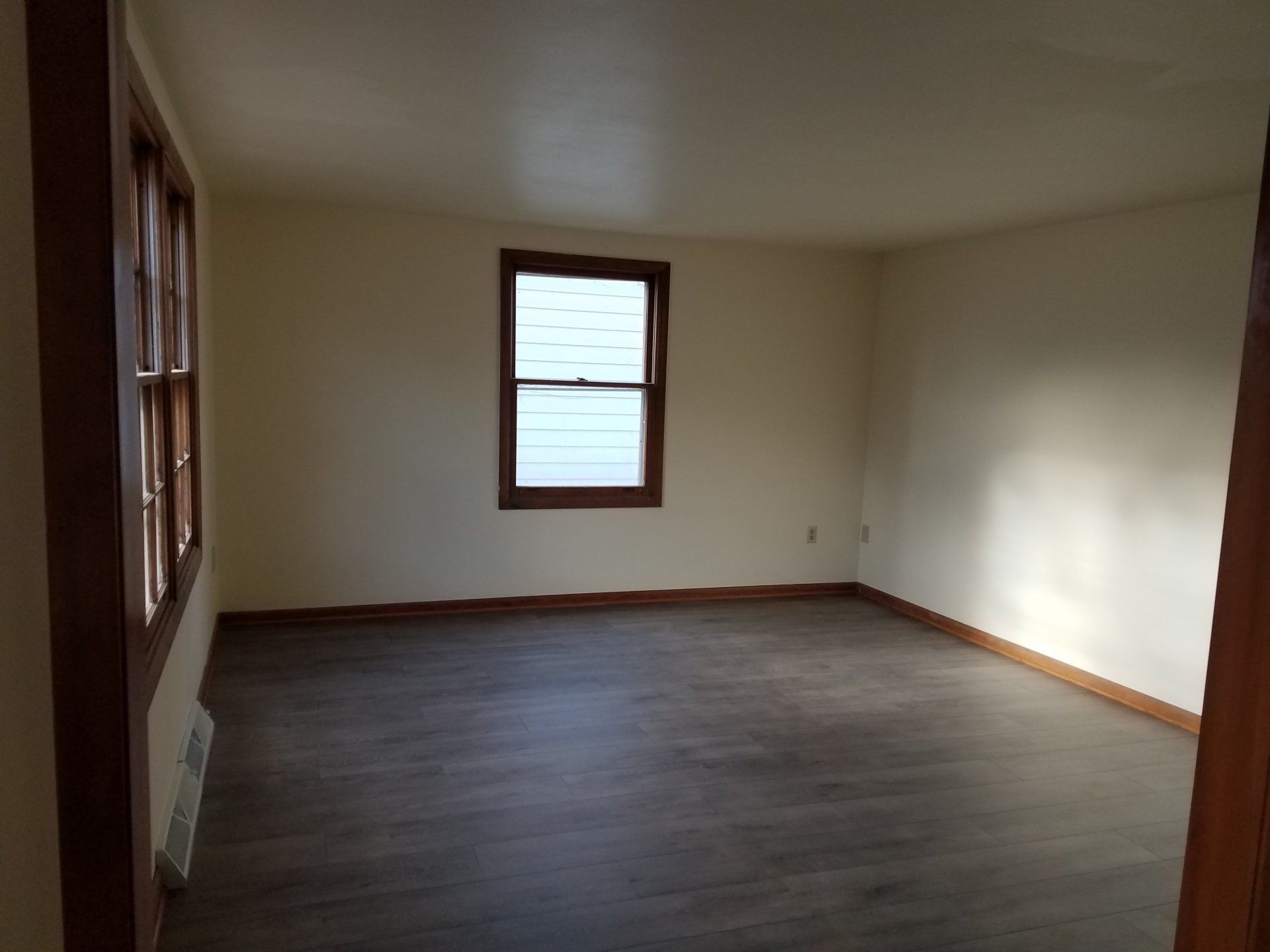 Bedroom with grey floor and windows.