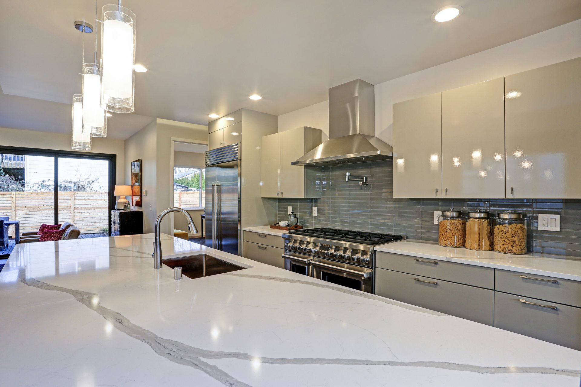 Sleek modern kitchen design with a long center island fitted with a gray and white quartz countertop.