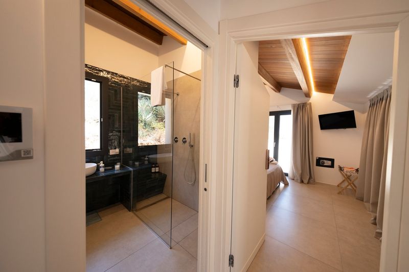 Camera da letto con porte finestre che si aprono sul balcone, con vista soleggiata sul mare e sul cielo azzurro.
