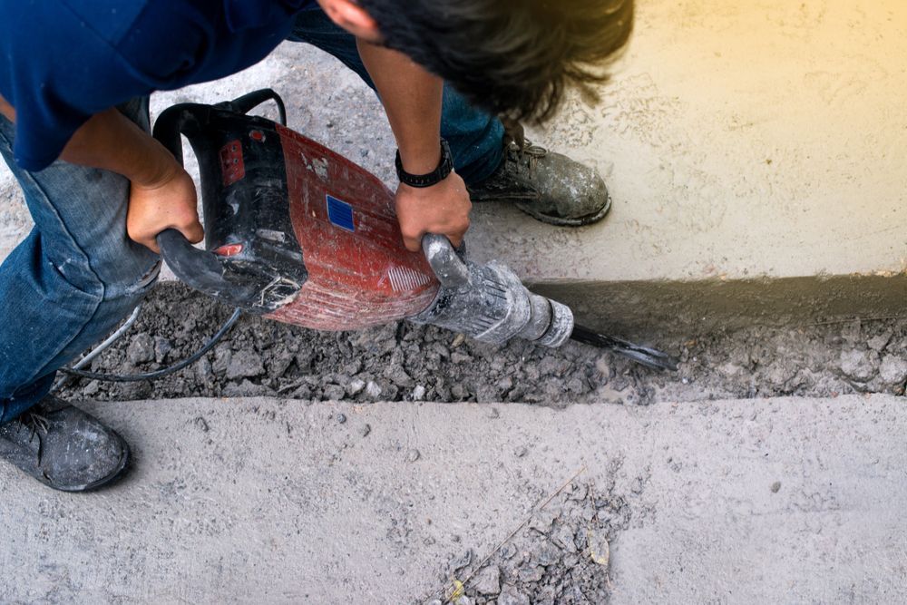 Person Uses a Jackhammer to Break up Concrete, Outdoors — Ultra Services Ground Pavement & Building in Cowra, NSW