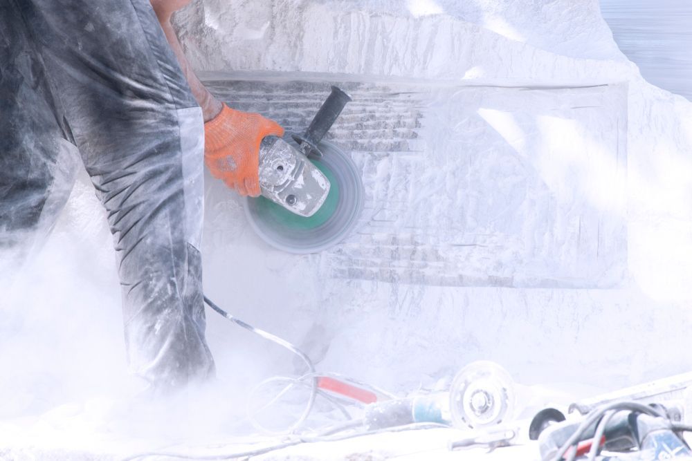 Person Using an Angle Grinder on A Stone Surface, Creating Dust — Ultra Services Ground Pavement & Building in Parkes, NSW