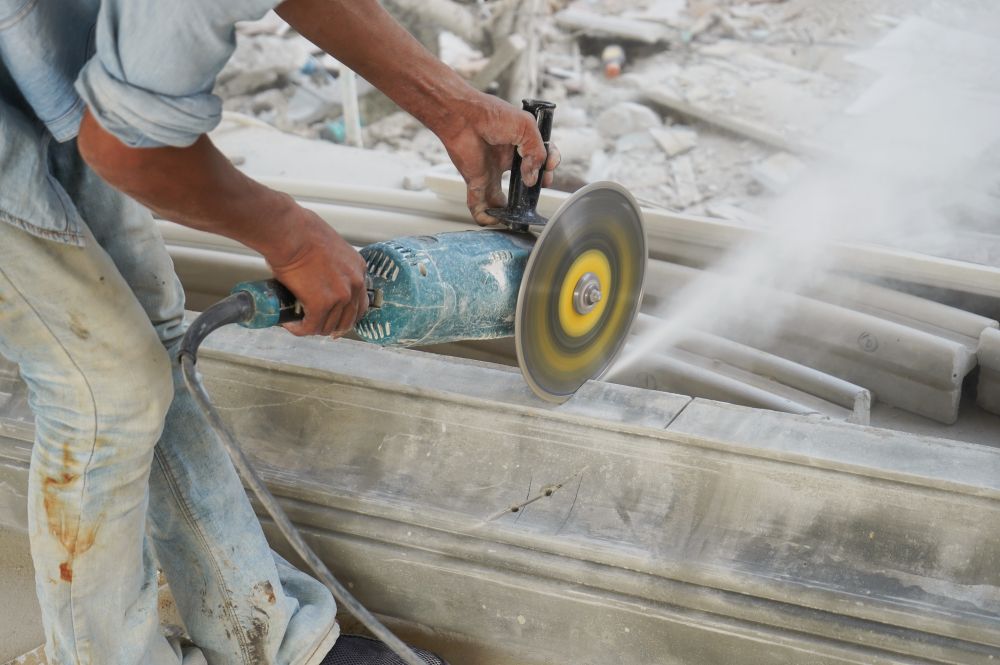 Person Using an Electric Grinder to Cut Stone — Ultra Services Ground Pavement & Building in Orange, NSW