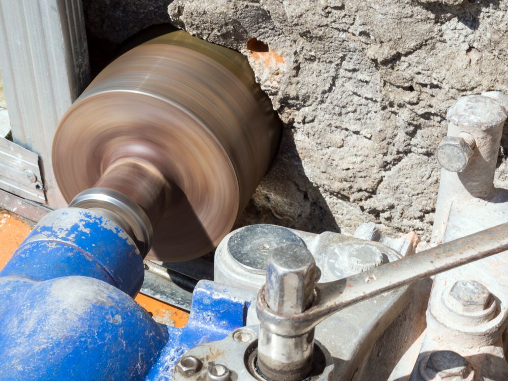 A Large, Spinning Drill Bit Bores Into a Concrete Wall — Ultra Services Ground Pavement & Building in Orange, NSW