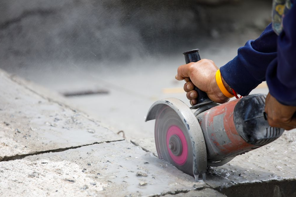 Person Using an Angle Grinder to Cut Concrete, Creating Dust — Ultra Services Ground Pavement & Building in Parkes, NSW