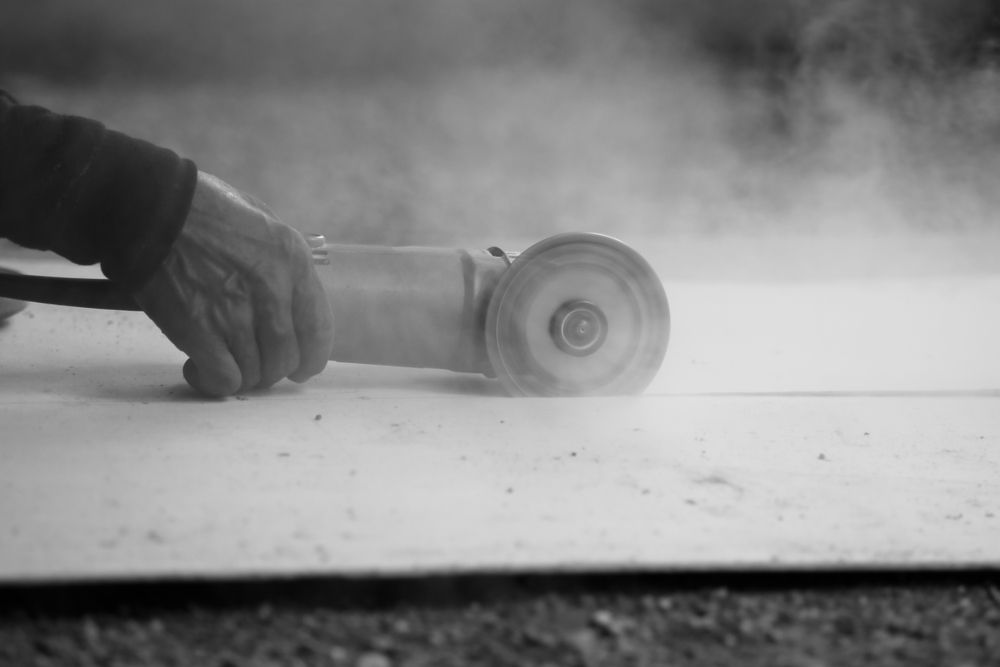 Person Using an Angle Grinder, Cutting Through a Surface — Ultra Services Ground Pavement & Building in Cowra, NSW