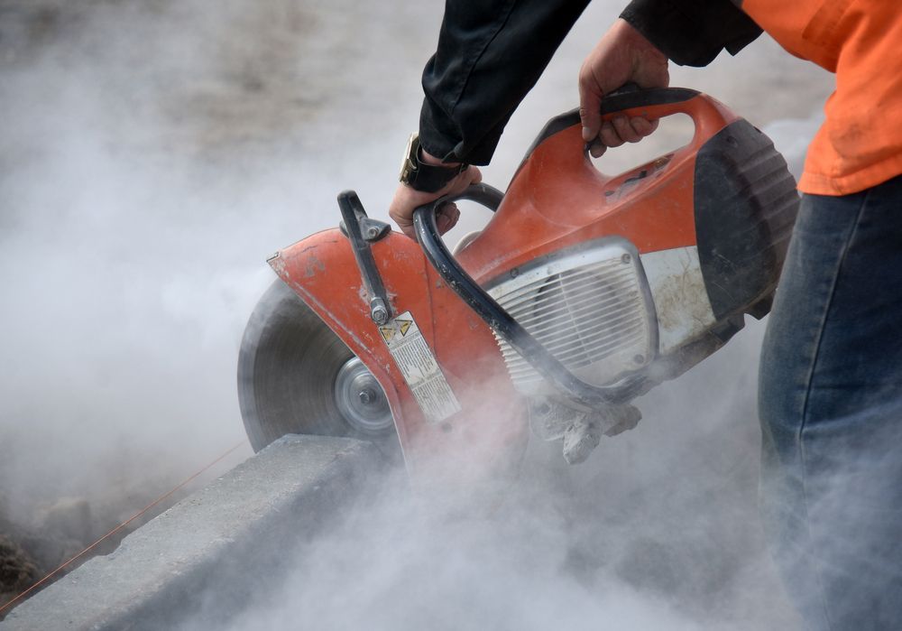 Person in An Orange Safety Vest Uses a Power Saw to Cut Concrete — Ultra Services Ground Pavement & Building in Mudgee, NSW