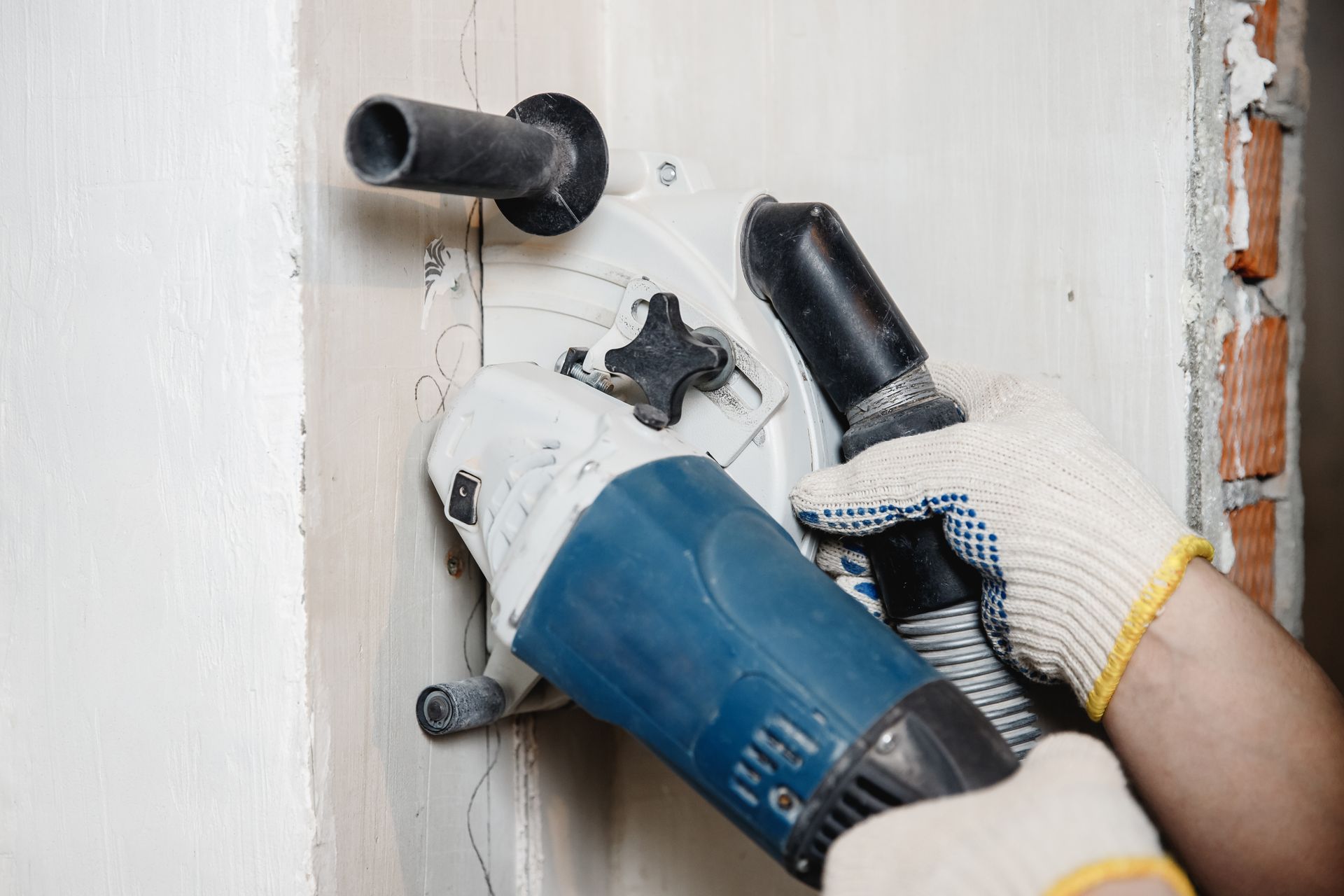 Person Using a Wall Chaser to Cut a Channel in A White Wall — Ultra Services Ground Pavement & Building in Mudgee, NSW