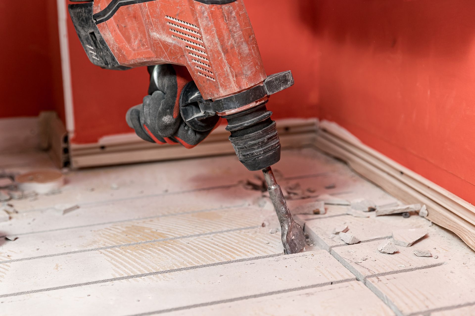 A Person Uses a Red Jackhammer to Break up A Concrete Floor — Ultra Services Ground Pavement & Building in Abercrombie, NSW