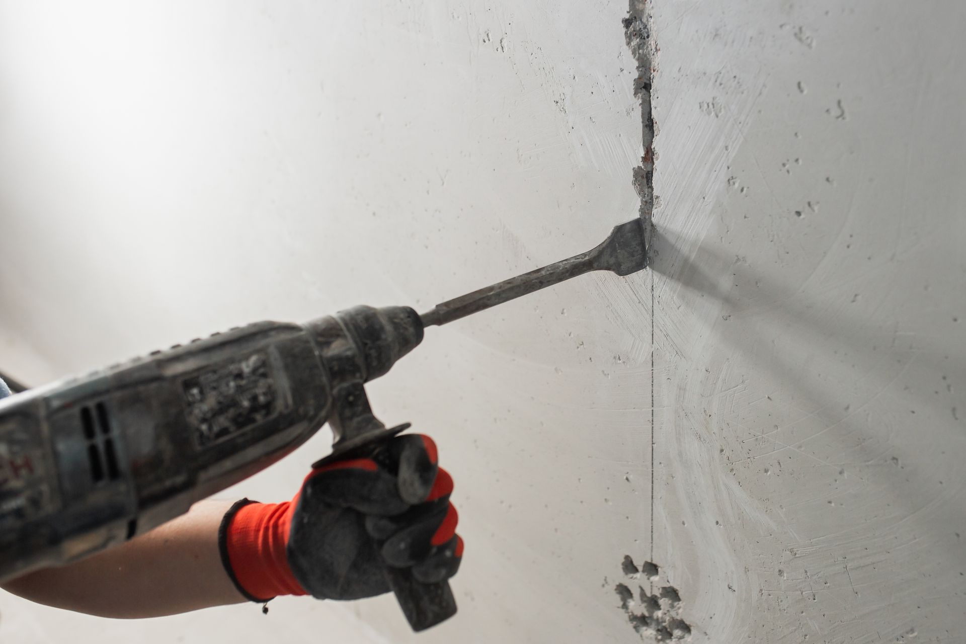 Person Using a Drill to Chisel Into a White Wall — Ultra Services Ground Pavement & Building in Parkes, NSW
