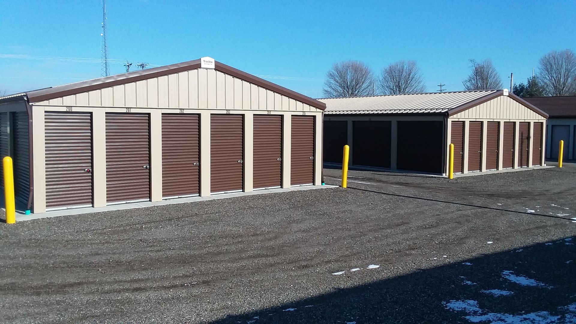 A group of storage units are sitting next to each other in a gravel lot.