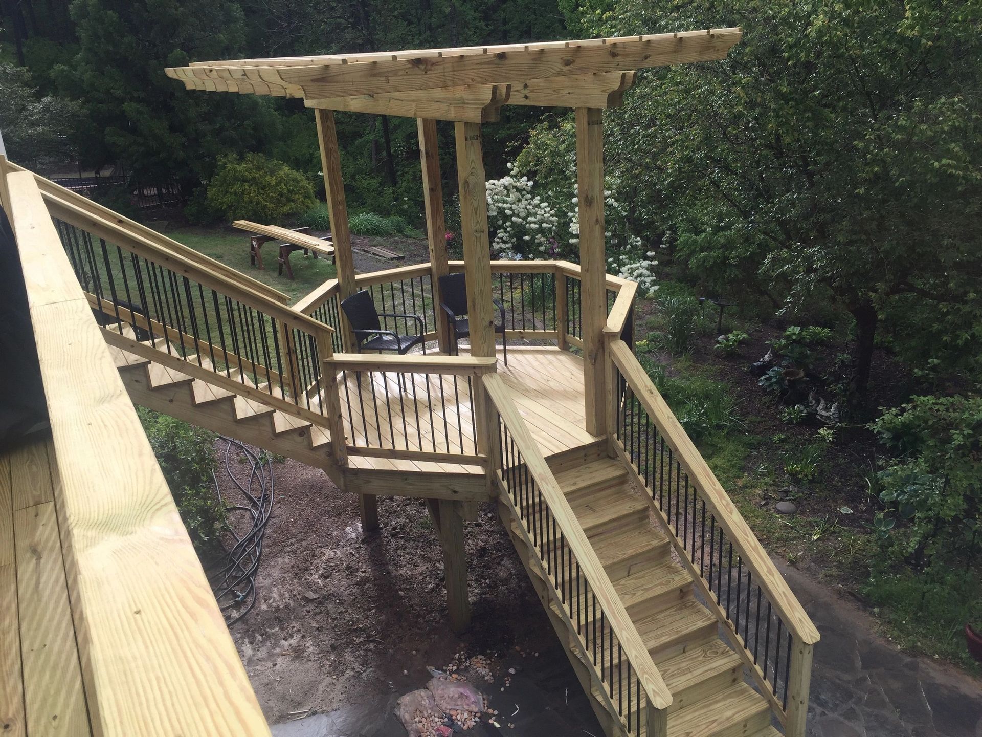 A wooden deck with stairs and a pergola over it