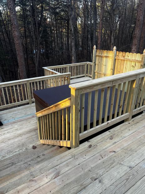 A wooden deck with a fence and a bench in the middle of the woods.