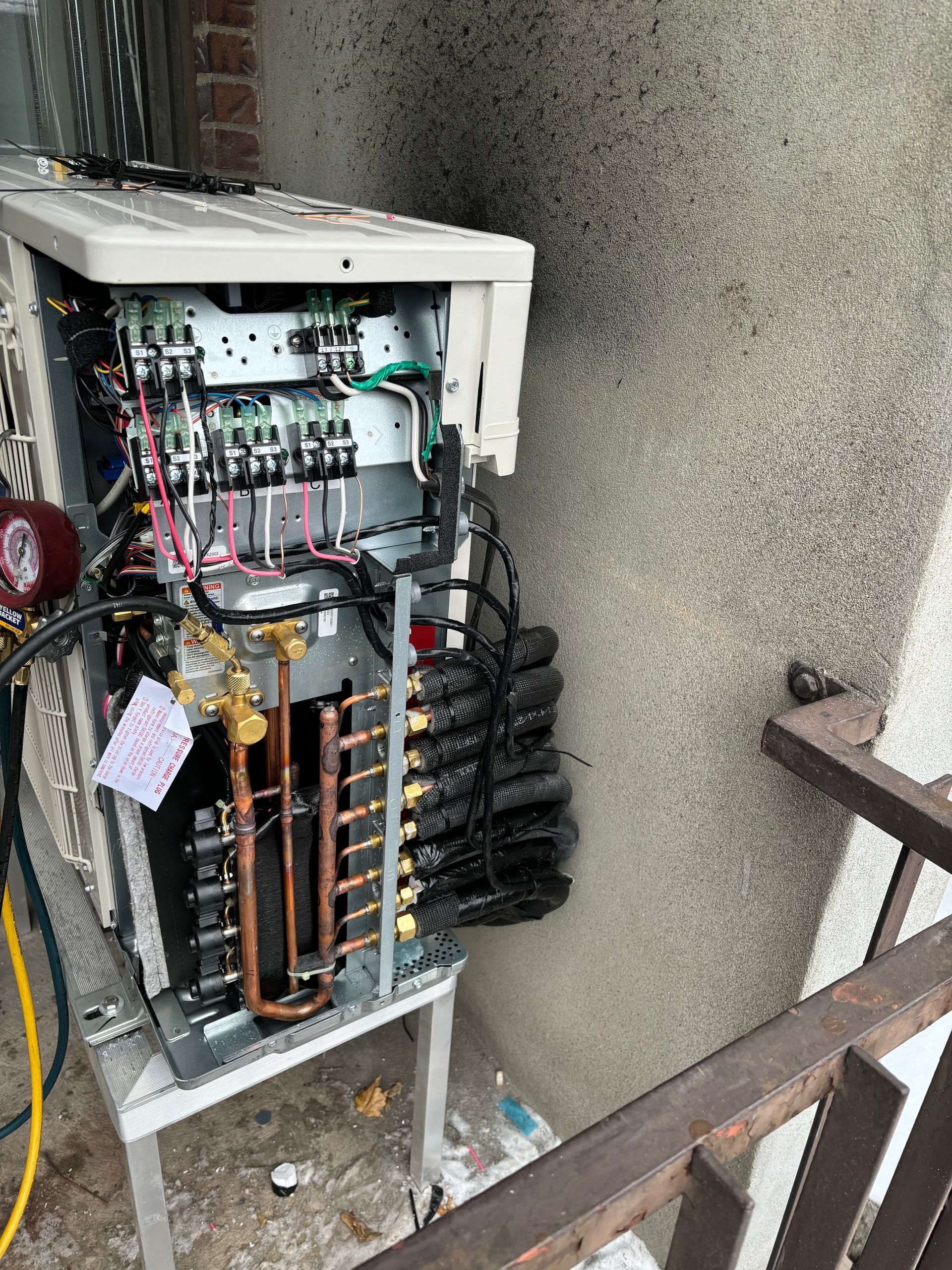 Un climatiseur cassé se trouve sur un balcon à côté d'une balustrade.