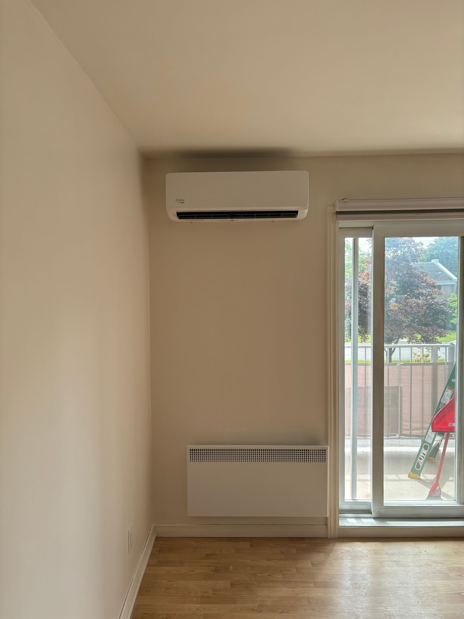 Une pièce vide avec une porte coulissante en verre et un climatiseur mural.