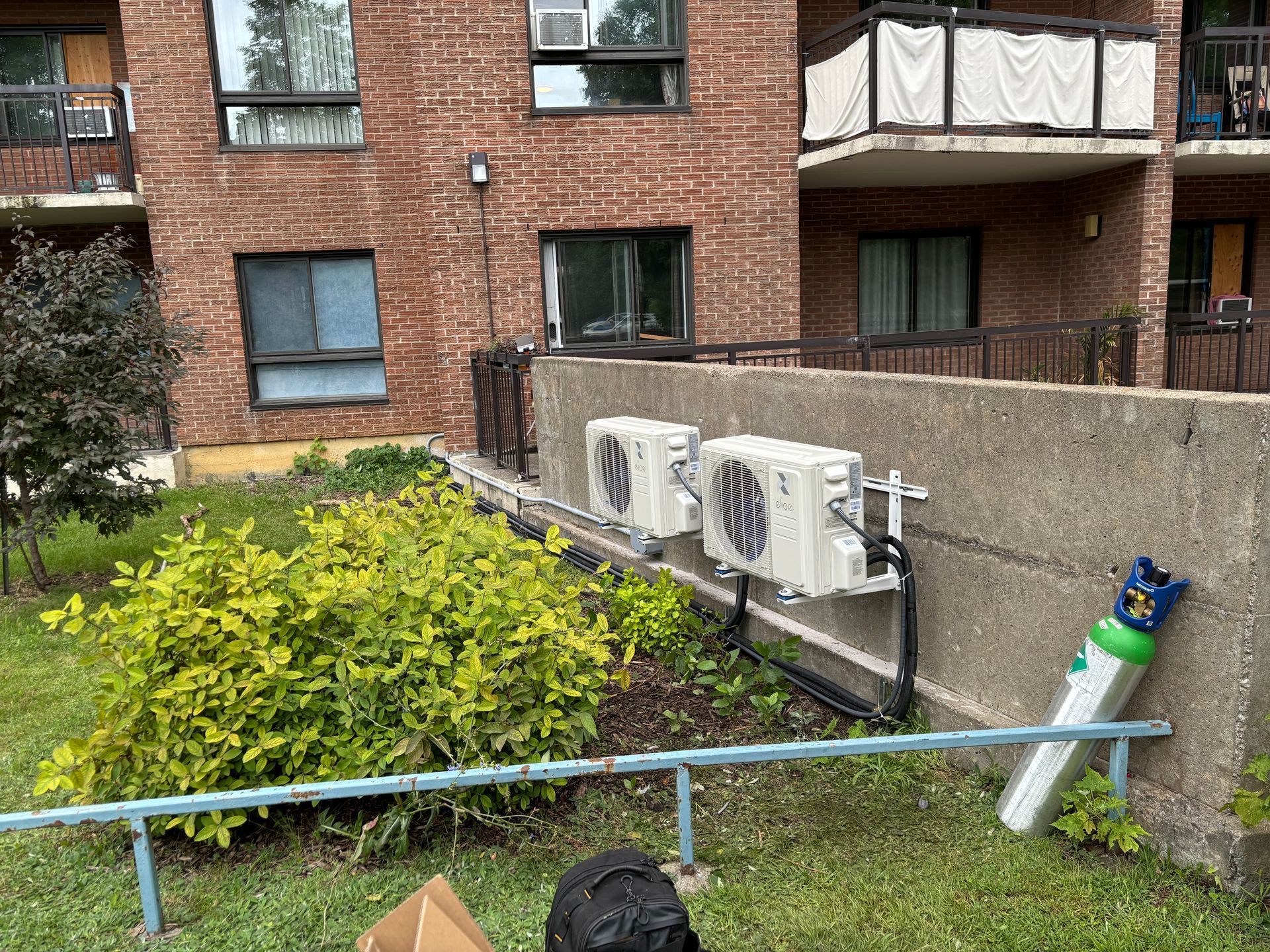 Un homme se tient devant un bâtiment en briques avec des climatiseurs sur le côté.