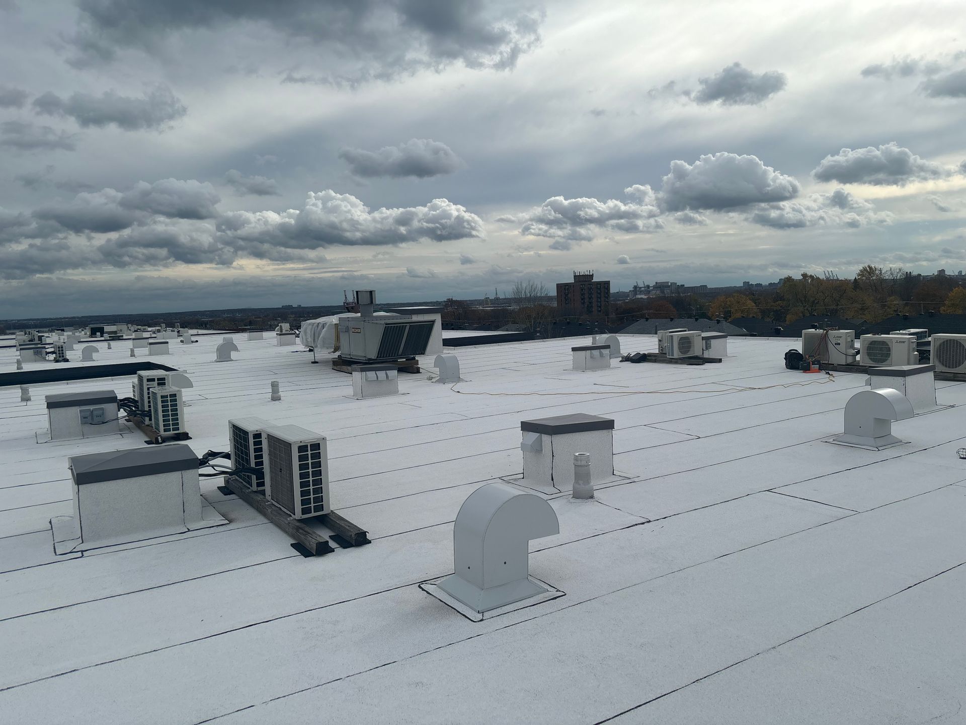 Un grand toit blanc avec beaucoup de tuyaux de ventilation dessus