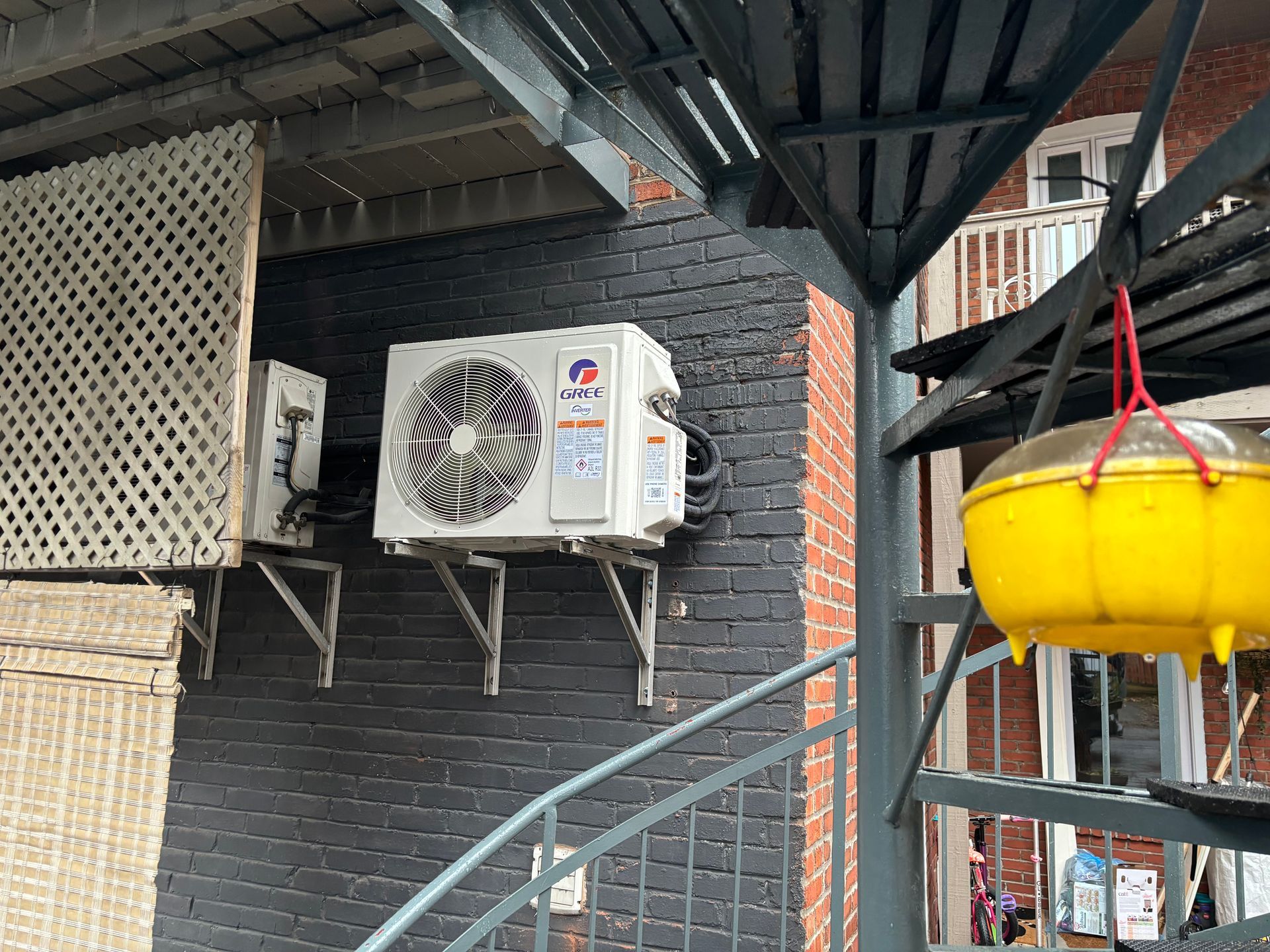 Un climatiseur est monté sur le côté d'un bâtiment à côté des escaliers.