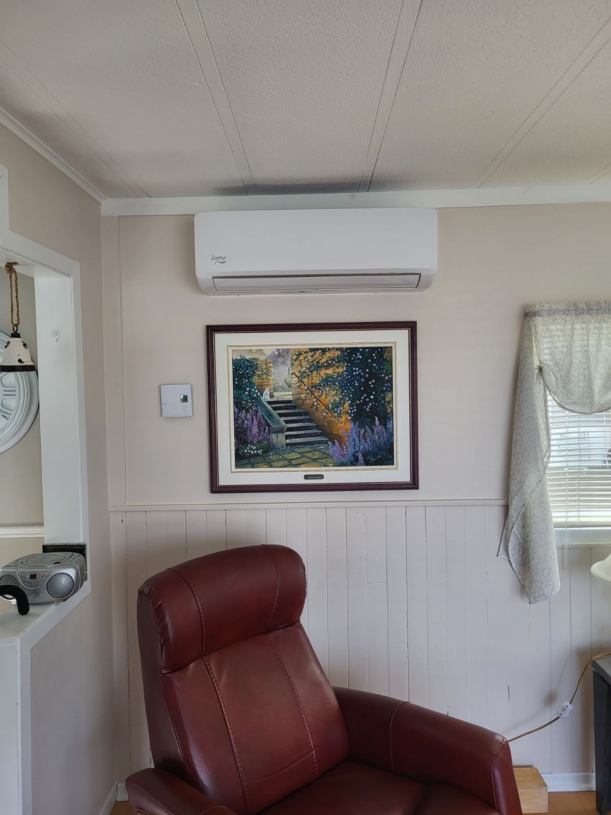 Un salon avec une chaise rouge et un tableau sur le mur.