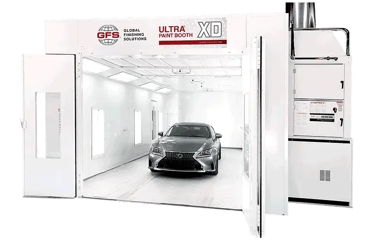 Car inside a white paint booth with open doors; industrial equipment visible.