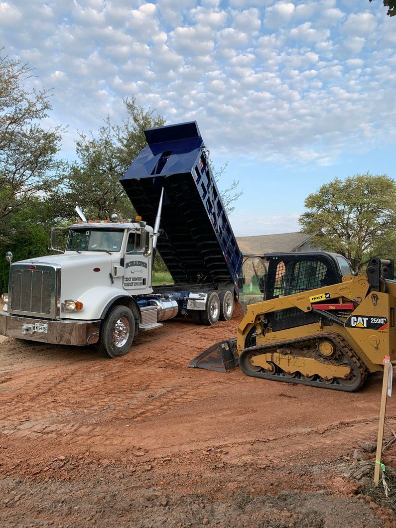 A dump truck is being loaded with dirt next to a bulldozer.