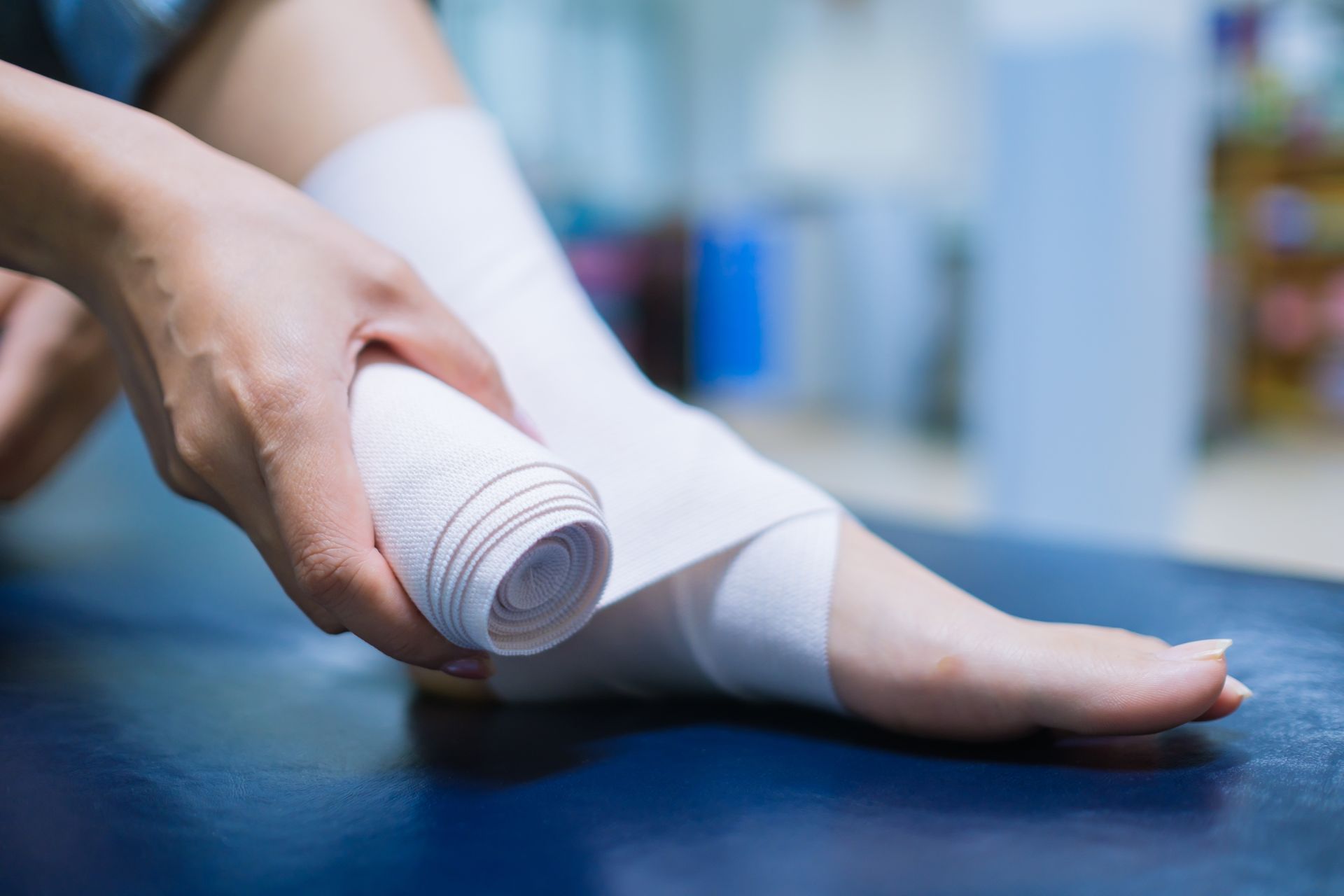 Person wrapping white bandage around their ankle.