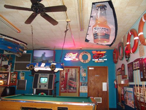 A pool table in a room with a corona bottle hanging from the ceiling